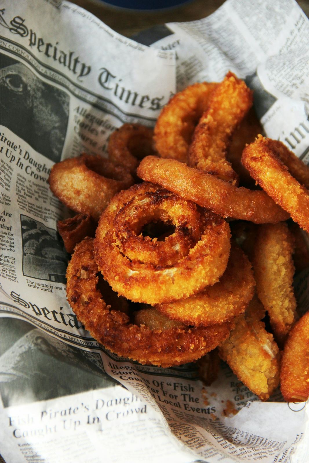 Basket of golden fried onion rings on newspaper